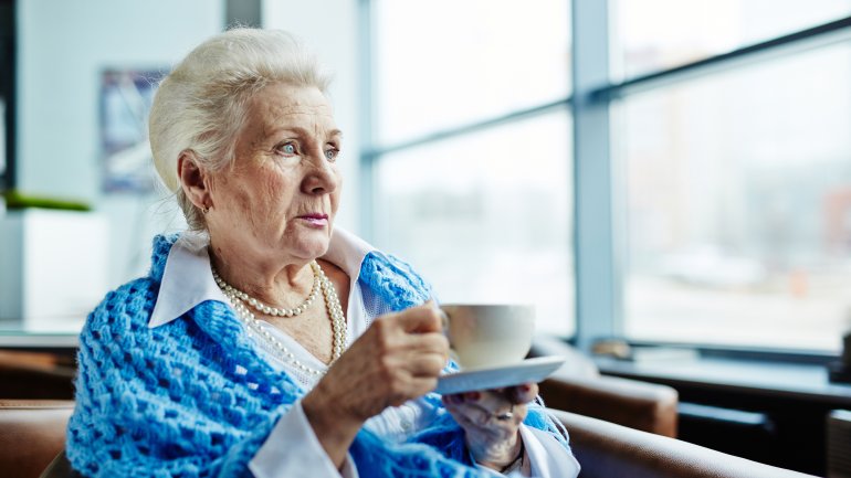 Weißhaarige ältere Frau mit Teetasse.