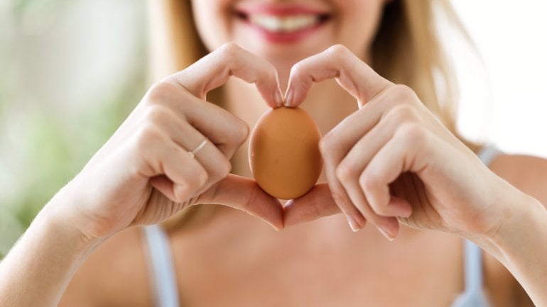 Frau mit Ei in der Hand und zeigt ein Herz