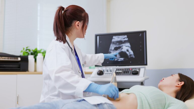 Frau mit Eierstockzyste wird von einer Ärztin mittels Ultraschall untersucht.