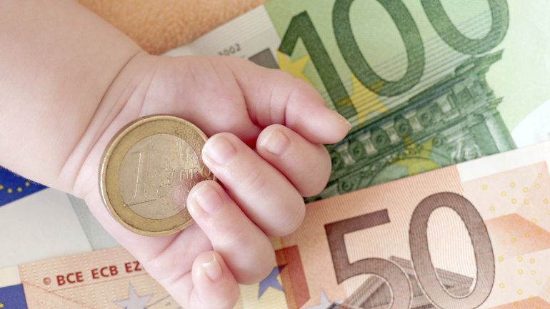 Babyhand mit Euroscheinen und Münze