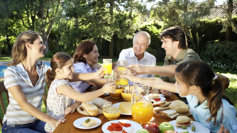 Das Bild zeigt eine Familie draußen beim Essen.