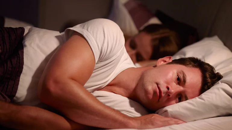 Ein Mann liegt neben seiner Partnerin im Bett.