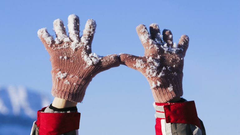 Das Bild zeigt eine Person mit Handschuhen im Schnee.