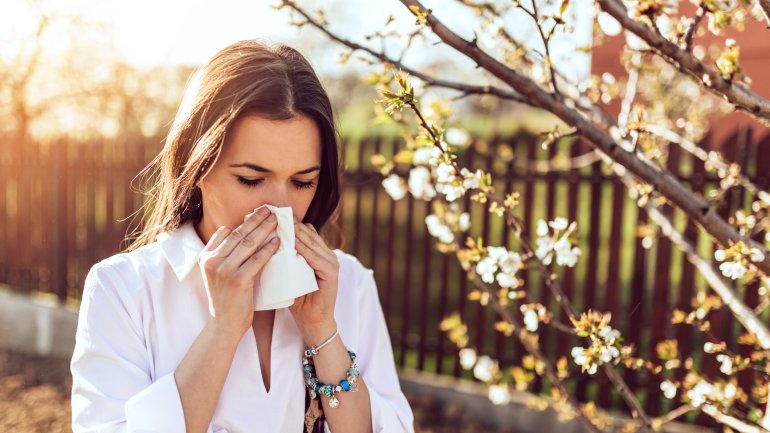 Sommergrippe: Eine Frau putzt sich die Nase.