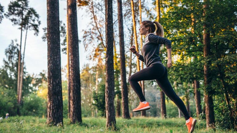 Eine Frau joggt (läuft) im Wald.