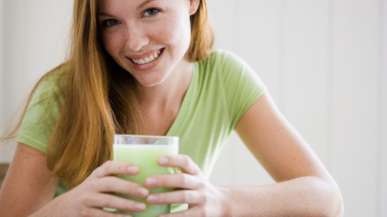 Das Bild zeigt eine Frau, mit einem Getränk in der Hand.