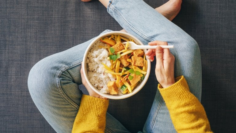 Eine Frau isst Reis mit Tofu