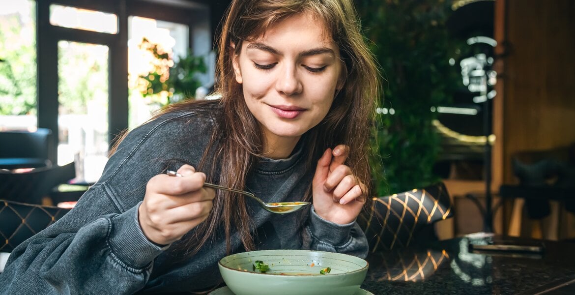 Eine Frau genießt einen Teller mit Gemüsesuppe