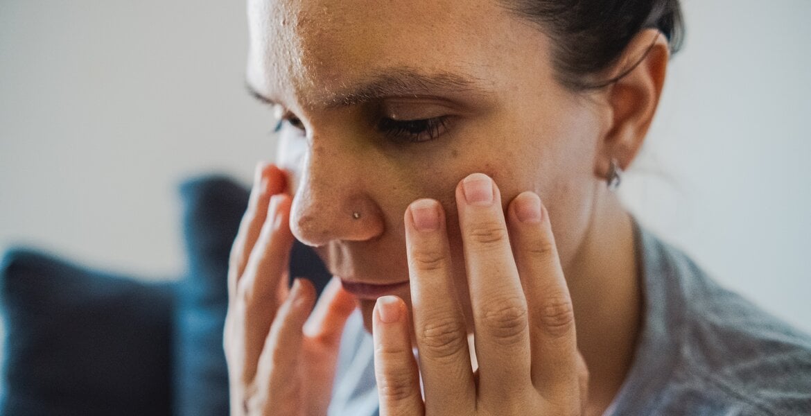 Leberzirrhose: Eine Nahaufnahme einer Frau die sich bedrückt ins Gesicht fasst