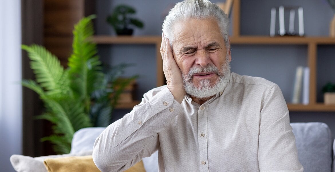Ohrenkrebs: Älterer Mann hält sich das Ohr und hat Schmerzen