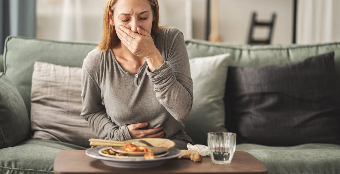 Pankreasinsuffizienz Symptome: Junge Frau hat Druckgefühl im Bauch nach dem Essen