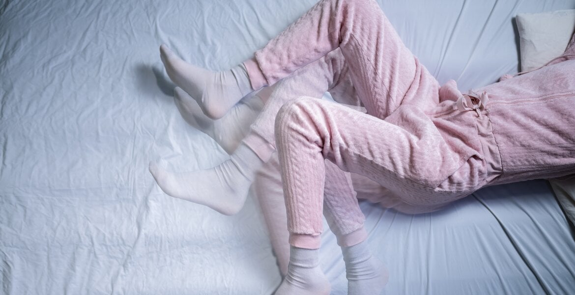 Bild einer Frau mit unruhigen Beinen nachts, die Symptom des Restless-Legs-Syndroms sind.