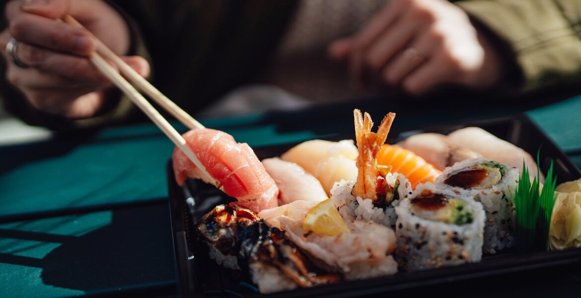 Frau isst Sushi, das zu den verbotenen Lebensmitteln bei Leberzirrhose zählt.