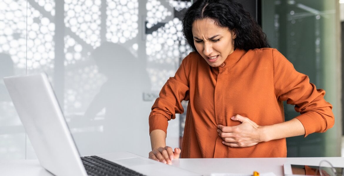 Frau hat starke Oberbauchschmerzen, die Symptom eines Zwölffingerdarmgeschwür sein können.