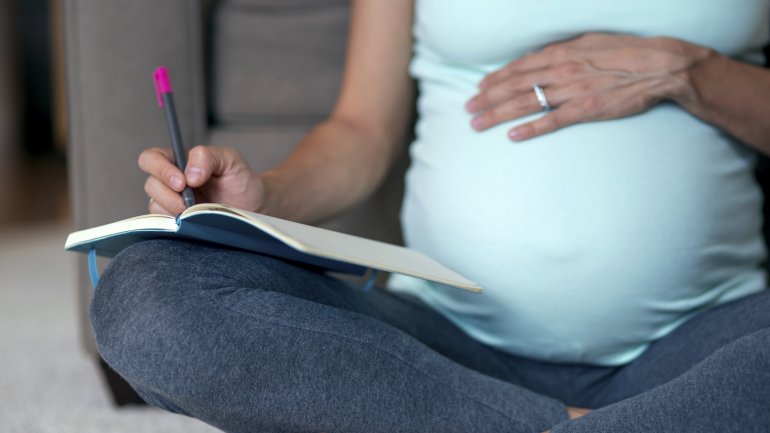 Schwangere schreibt in ein Notzibuch
