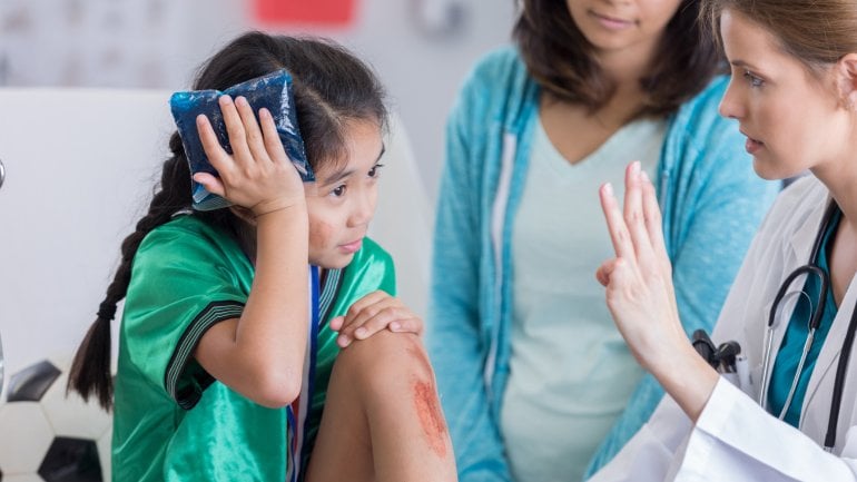 Ein Mädchen mit einer Kopfverletzung wird von einer Ärztin auf eine Gehirnerschütterung hin untersucht