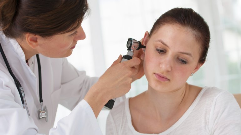 Das Bild zeigt eine Ärztin, die das Ohr einer Frau untersucht.