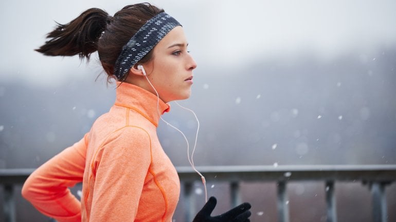 Das Bild zeigt eine Frau, die im Winter joggt.