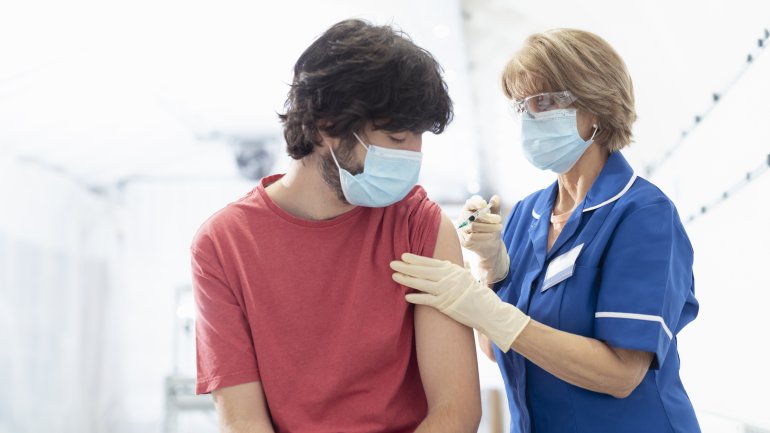 Ein junger Mann mit Mundschutz wird geimpft