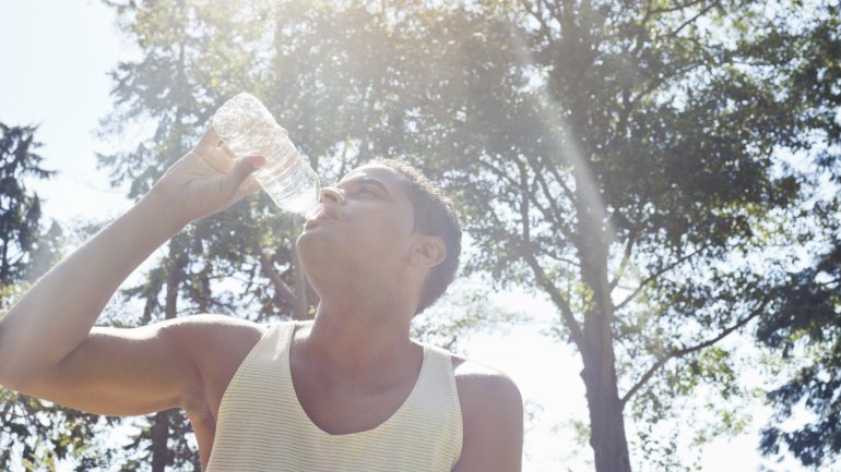 Hitzeerschöpfung: Mann trinkt aus einer Flasche Wasser