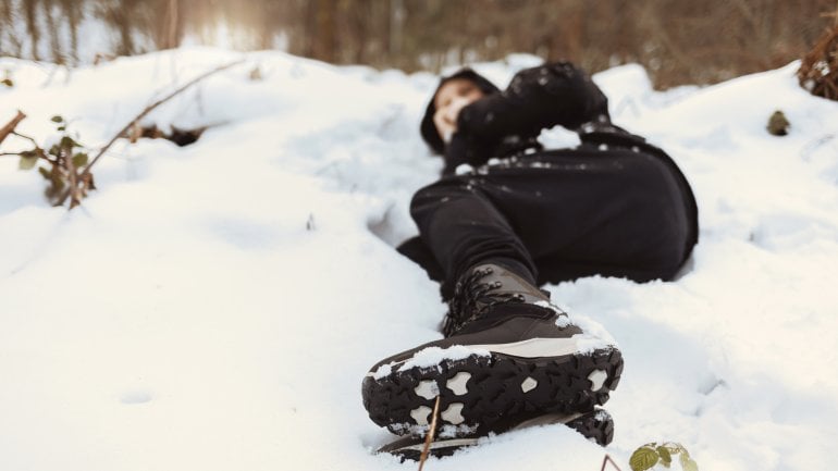 Hypothermie: Person liegt im Schnee und hat eine Unterkühlung.