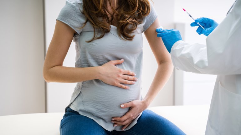Eine schwangere Frau wird von einem Arzt geimpft.