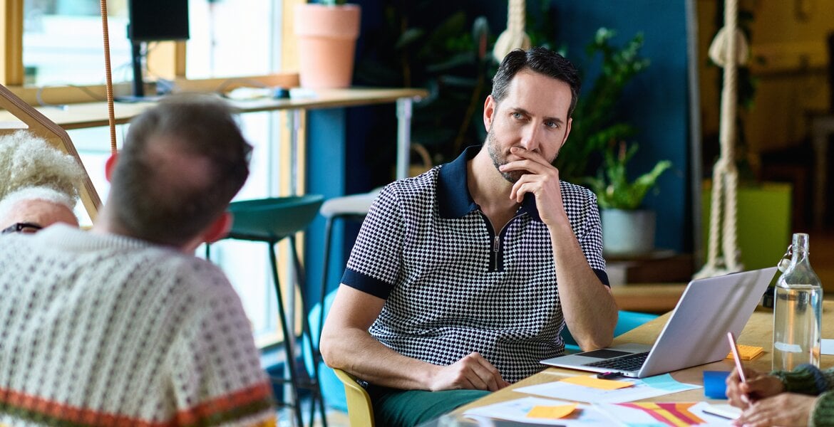 Zwei Männer sitzen im Büro und unterhalten sich, einer sieht den anderen sehr unsicher an