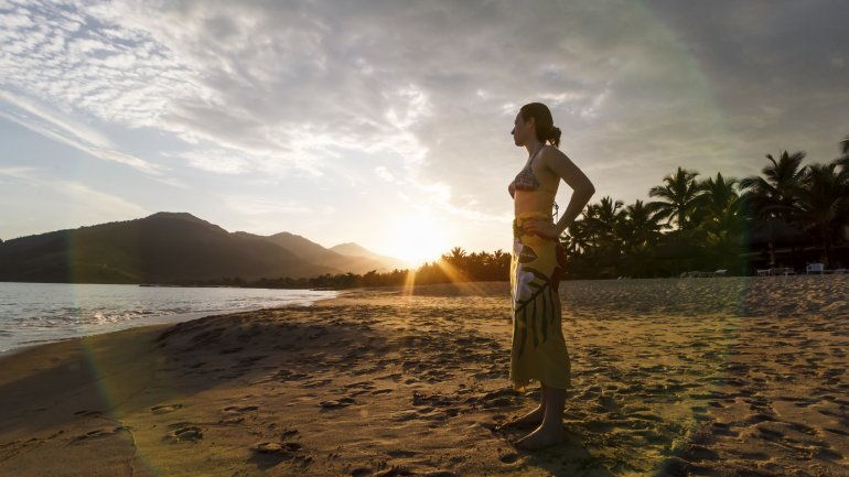 Ein Frau steht am Strand und blickt aufs Meer hinaus.