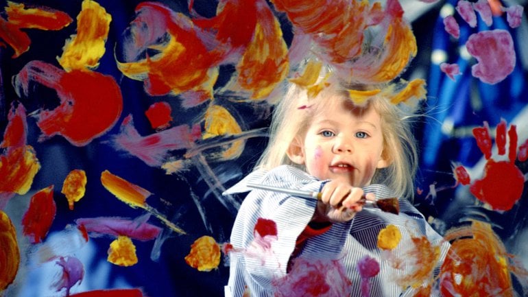 Mädchen malt eine Glasscheibe bunt an