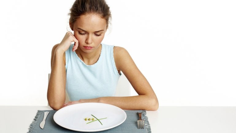 Das Bild zeigt eine Frau, die von einem fast leeren Teller sitzt. 