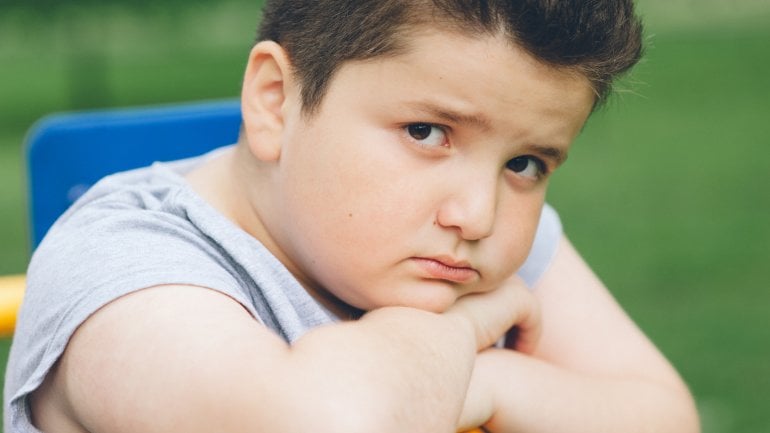 Ein übergewichtiger Junge schaut traurig in die Kamera.