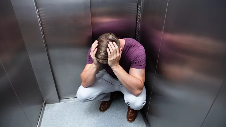 Ein Mann fühlt sich sichtlich unwohl im Aufzug.