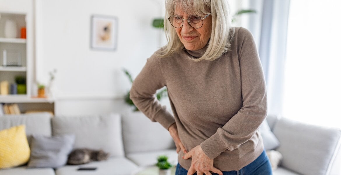 Ältere Frau fasst sich wegen Schmerzen an die Hüfte