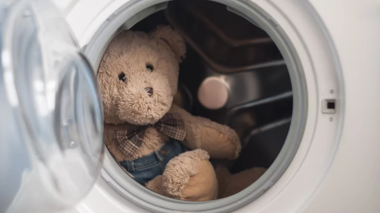 Ein Teddybär sitzt in einer Waschmaschine.