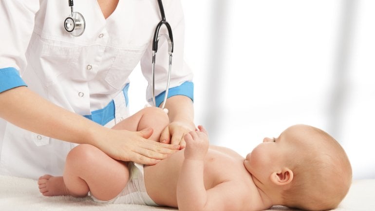 Eine Ärztin tastet den Bauch eines Babys ab.