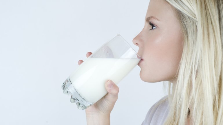 Eine blonde Frau trinkt ein Glas Milch.
