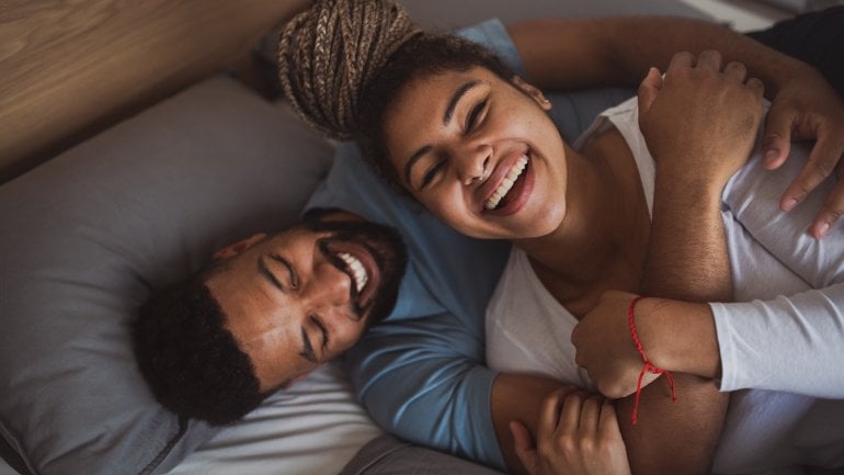 Libido: Junges Paar im Bett lacht gemeinsam.