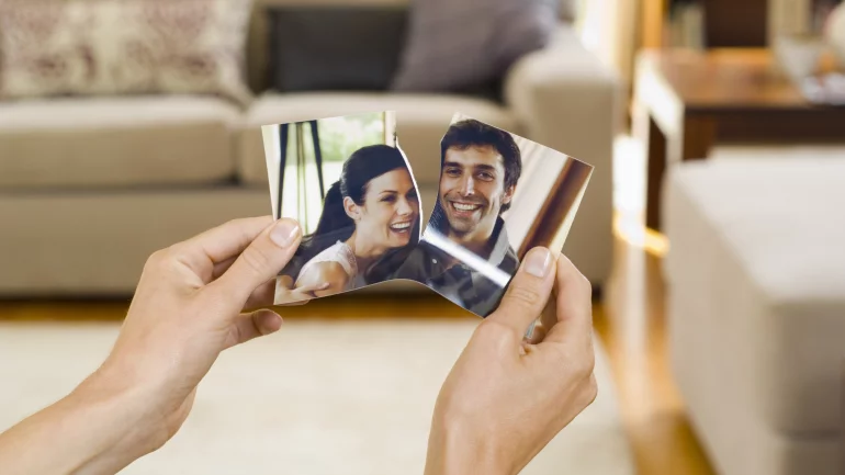 Jemand zerreißt ein Foto, auf dem ein junges Paar zu sehen ist.