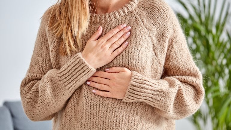 Frau mit Lungenembolie hält sich schmerzende Brust.