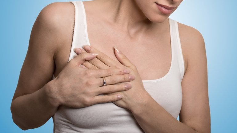 Eine Frau greift sich an die schmerzende rechte Brust.
