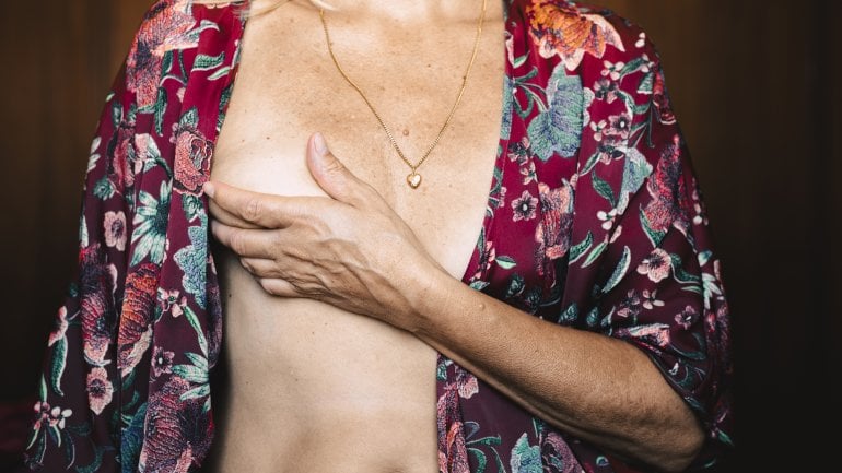 Frau mit Mastopathie fasst sich an Brust.