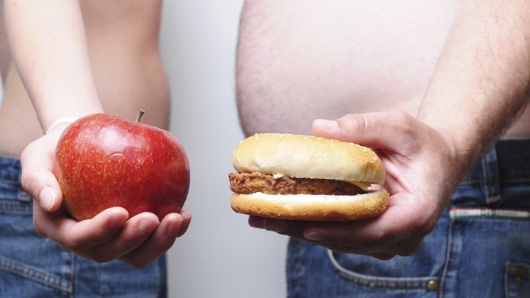 Das Bidl zeigt eine Frau, die einen Apfel hält und einen Mann, der einen Burger hält.
