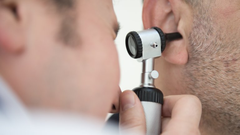 Ein Hals-Nasen-Ohren-Arzt untersucht das Ohr eines Patienten.