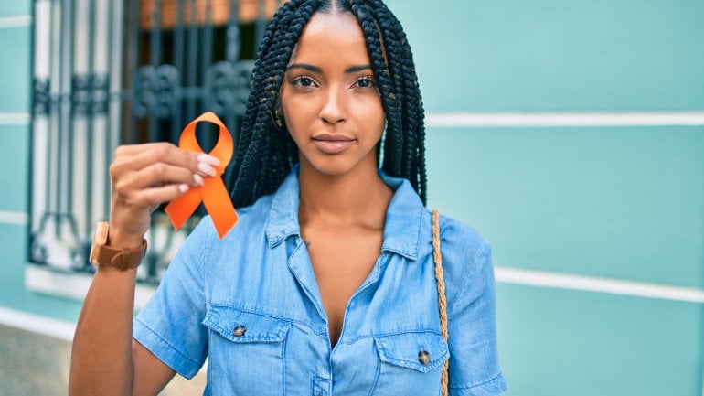 Multiple Sklerose: Eine junge Frau mit oranger Schleife