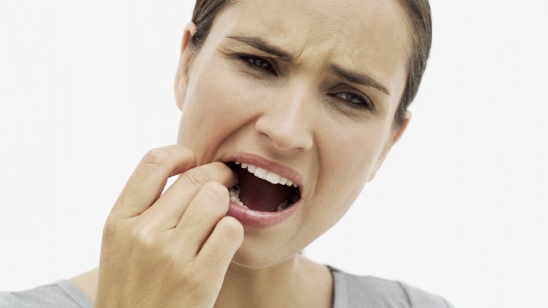 Das Bild zeigt eine Frau, die Schmerzen im Mund hat.
