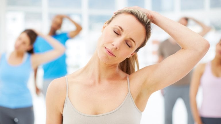 Eine Gruppe Erwachsener führt Übungen zur Dehnung der Nackenmuskulatur aus.