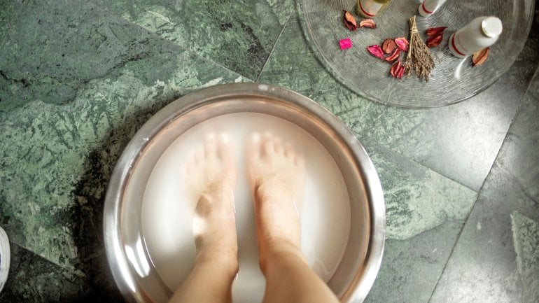 Die Füße einer Frau in einem Fußbad.