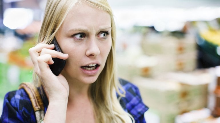 Eine ängstlich wirkende Frau telefoniert mit dem Handy.