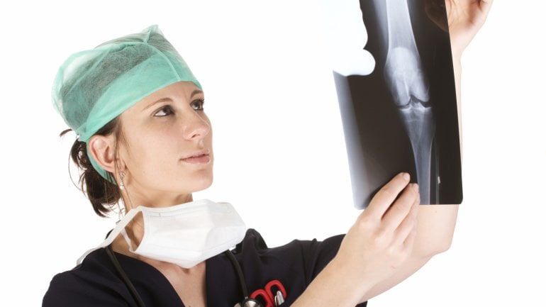 Das Bild zeigt eine Ärztin, die sich ein Röntgenbild ansieht. 
