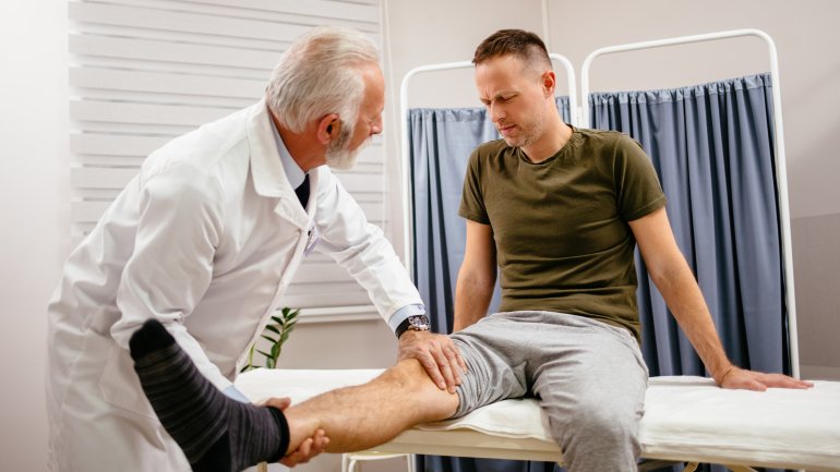 Ein Arzt untersucht eine Beinverletzung bei einem Mann
